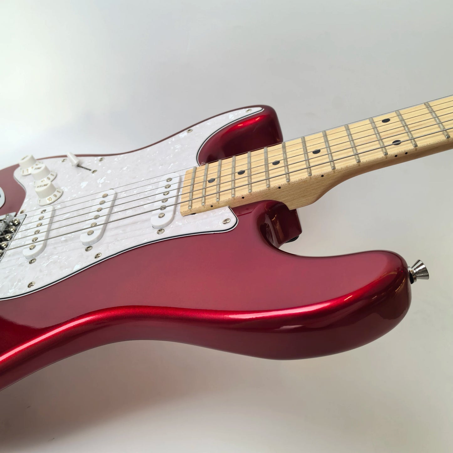 In stock, left-handed 6-string electric guitar in metallic red, made of mahogany with pearl pickguard. Ready to ship upon order!