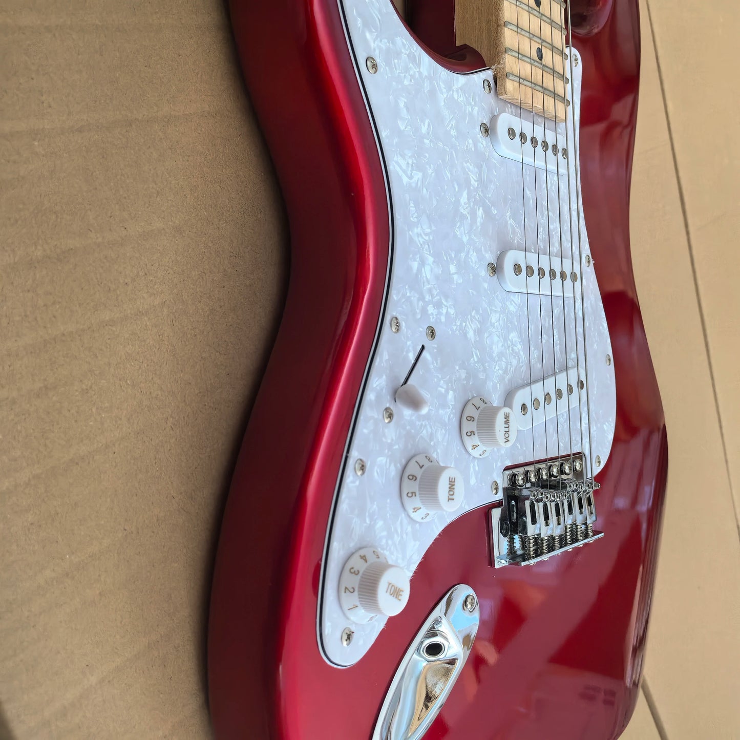 In stock, left-handed 6-string electric guitar in metallic red, made of mahogany with pearl pickguard. Ready to ship upon order!