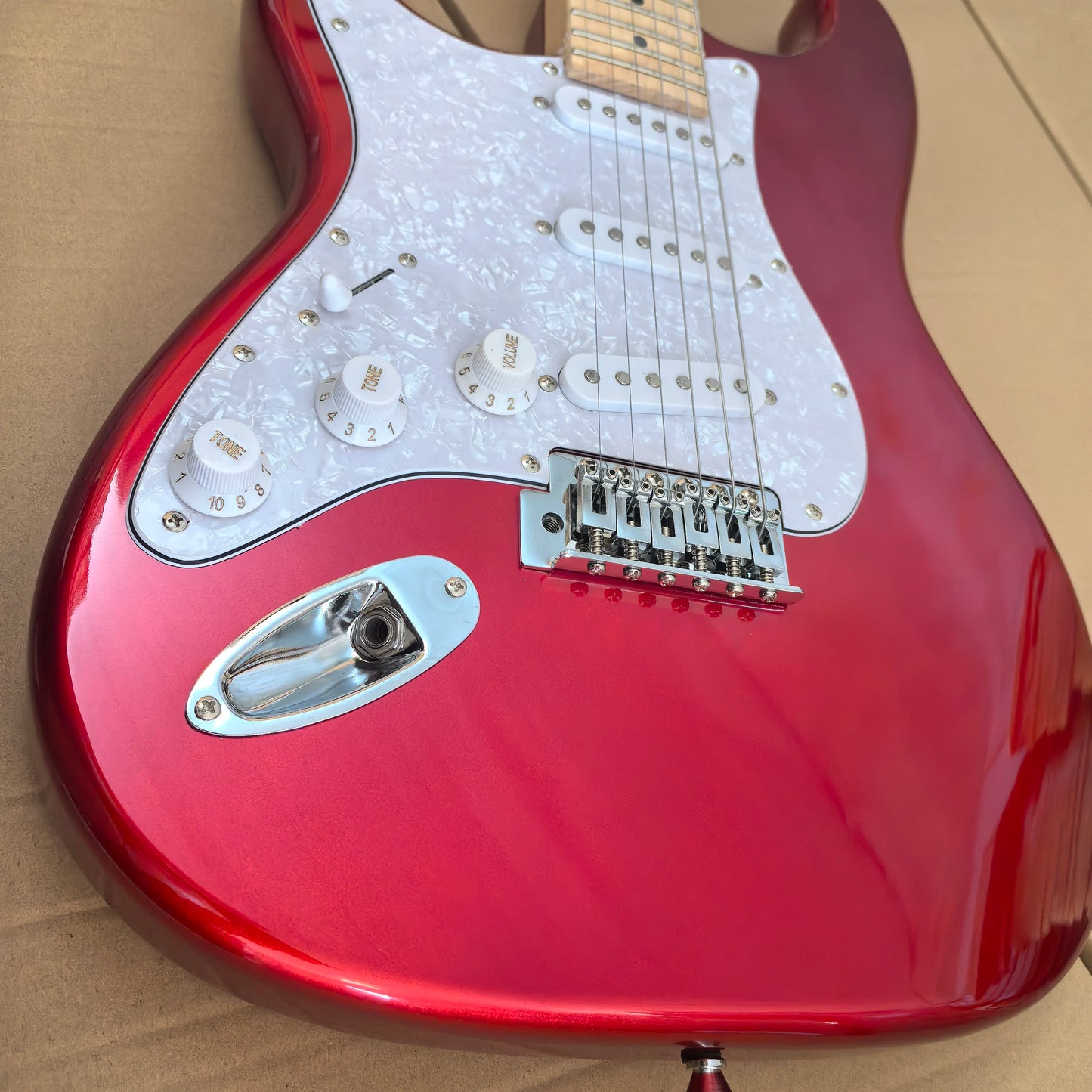 In stock, left-handed 6-string electric guitar in metallic red, made of mahogany with pearl pickguard. Ready to ship upon order!